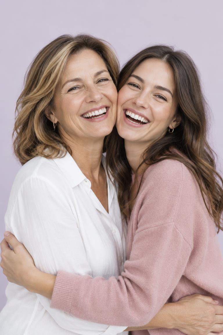 A mother and her adult daughter laughing in an embrace